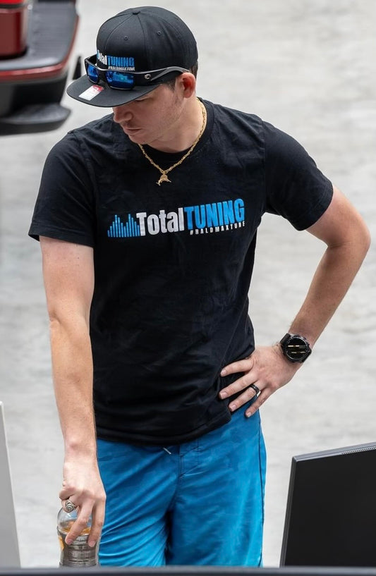 Person wearing a black 'Total Tuning' t-shirt with a blurred background