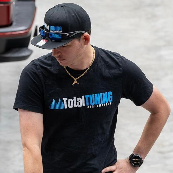 Person wearing a black 'Total Tuning' t-shirt with a blurred background
